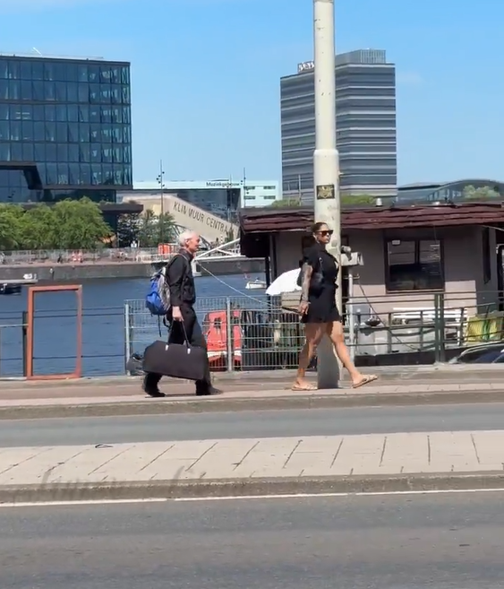 Femeie filmată în timp ce se plimbă și ține în lesă un bărbat cu părul alb