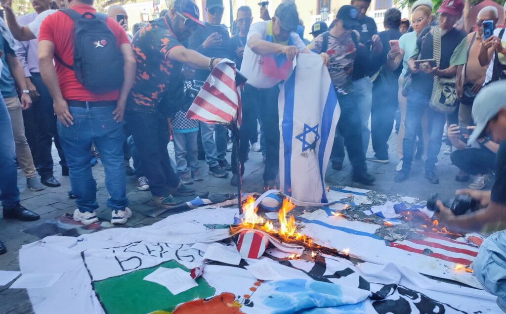La o lună după cutremurul din Venezuela, manifestanții pro-Maduro incendiază steagurile SUA și Israelului
